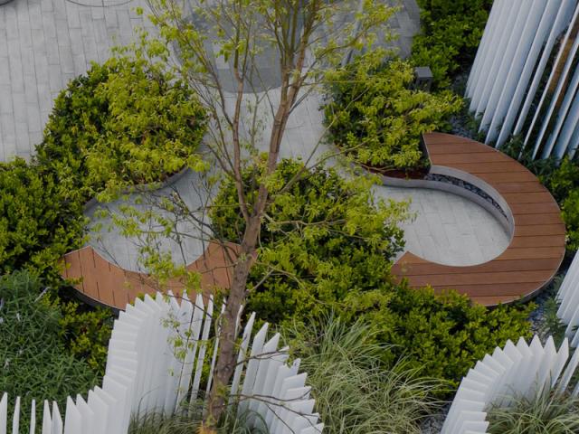 An exterior landscape deisgn with wavy fence like structures and sitting areas